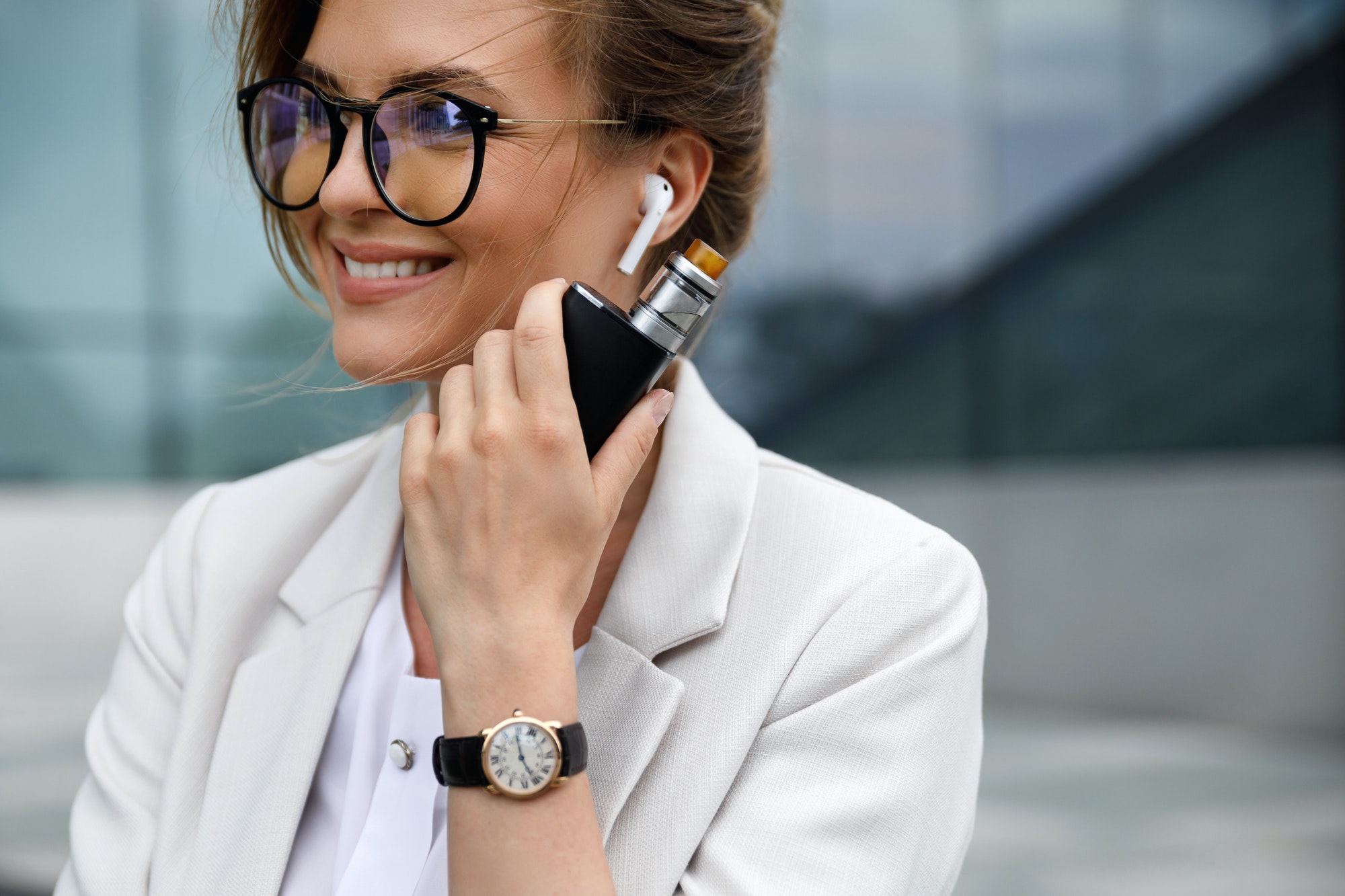 Young beautiful business woman smoking vape outside